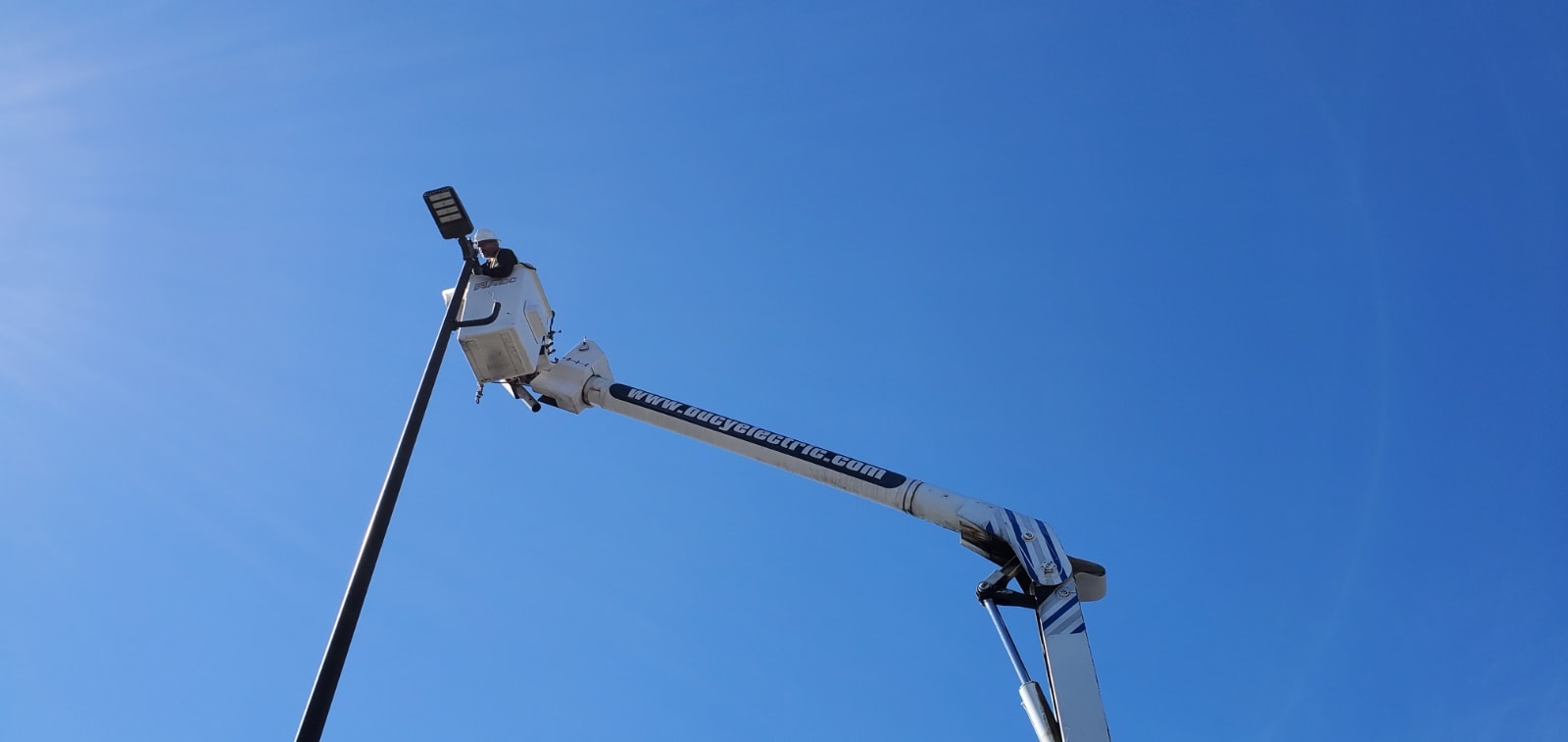 Bucy Electric bucket truck boom raised against a clear blue sky