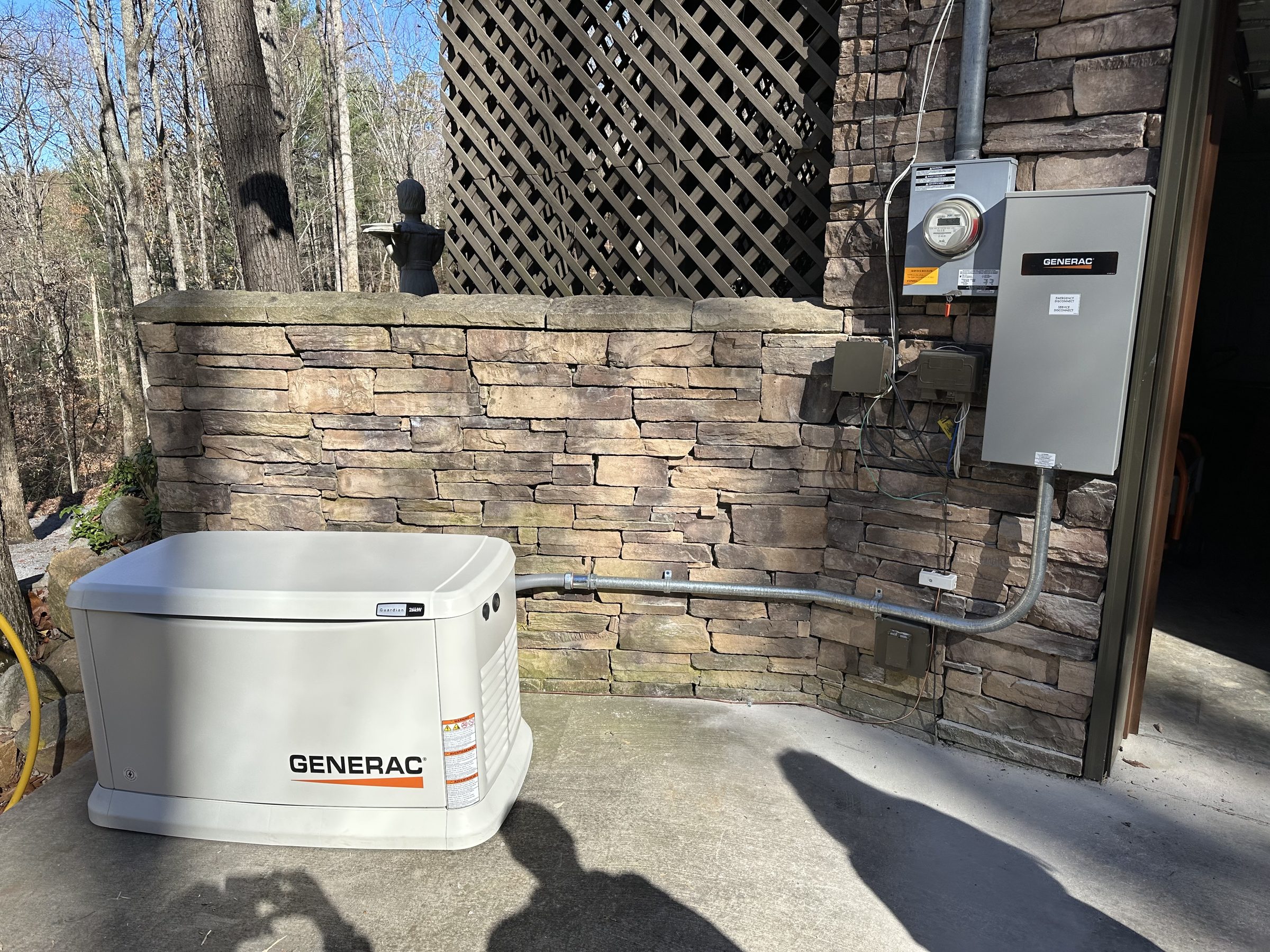 Generac standby generator installed beside a stone exterior wall